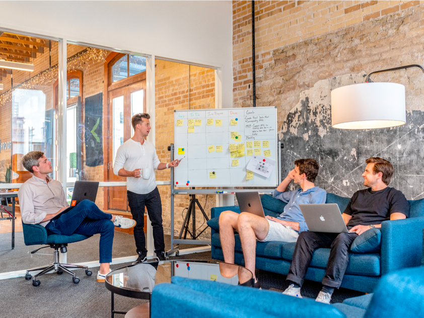 Four Businessmen having a meeting using a whiteboard with sticky notes on it