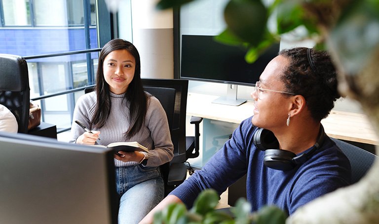 Two colleagues having conversation at work desk